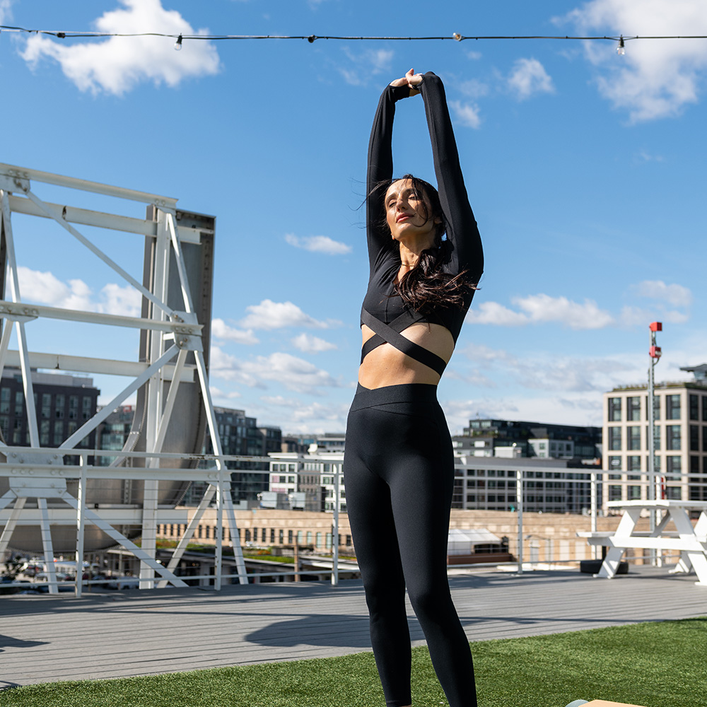 A young woman stretching on an outside apartment rooftop deck