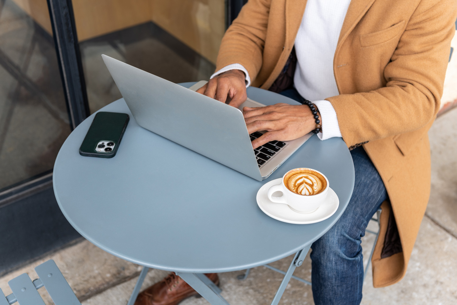 A Blue Bottle customer working on a laptop while enjoying a cappuccino