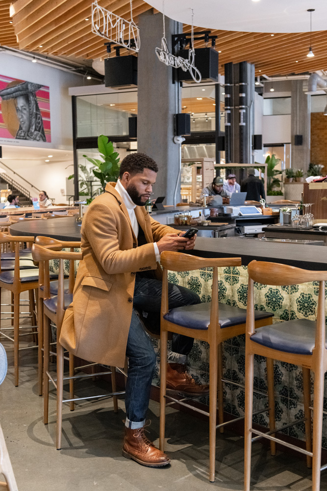 A man sitting in a stool at high-end bar and working on his phone