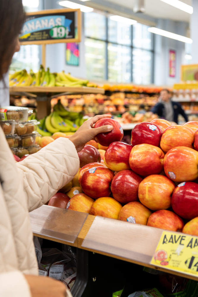 A woman grocery shopping for apples in a Trader Joes store