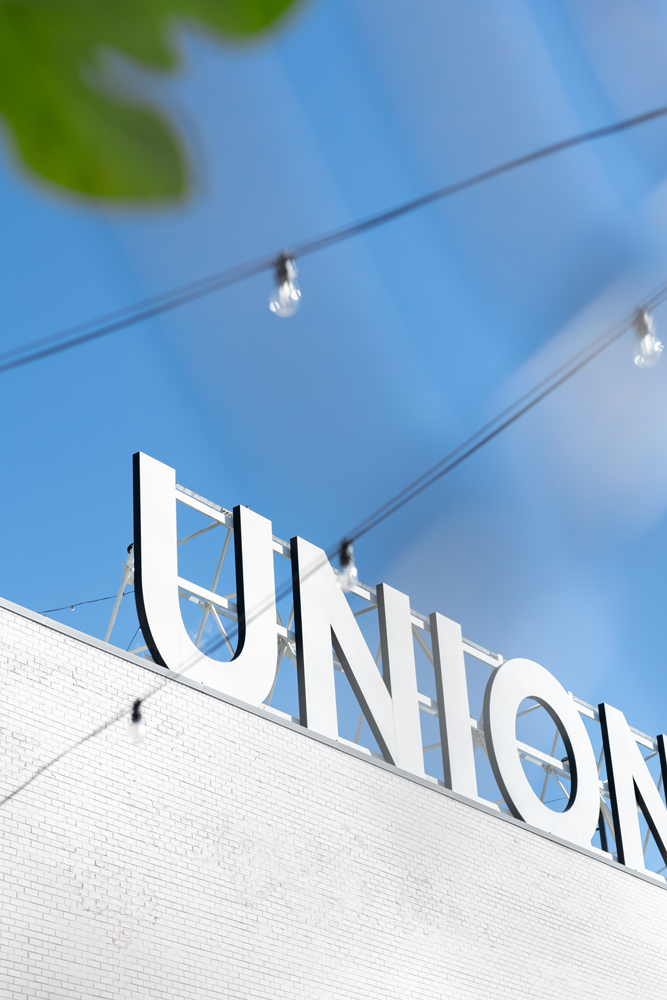 Sidewalk view of a white UNION sign on top of a brick building