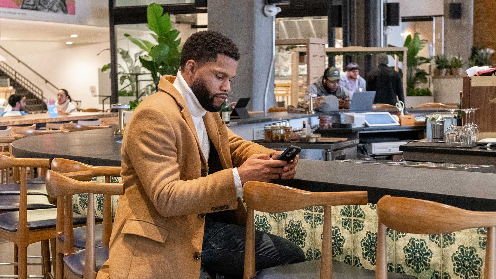 A young man sitting at a chic bar working on his phone