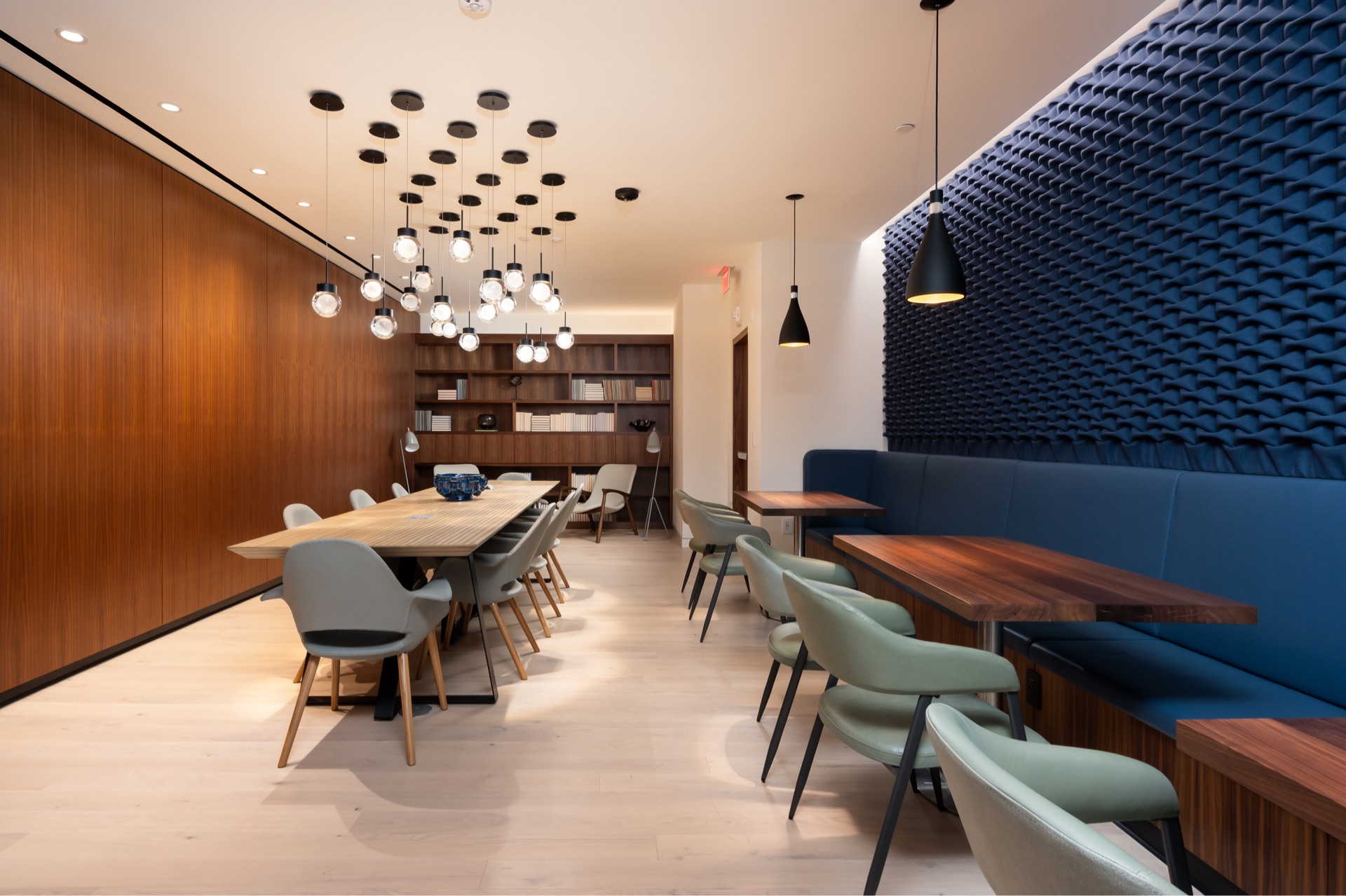 Margarite luxury apartments' coworking space in Washington, DC, with wooden walls, shelves, tables, & blue couches.